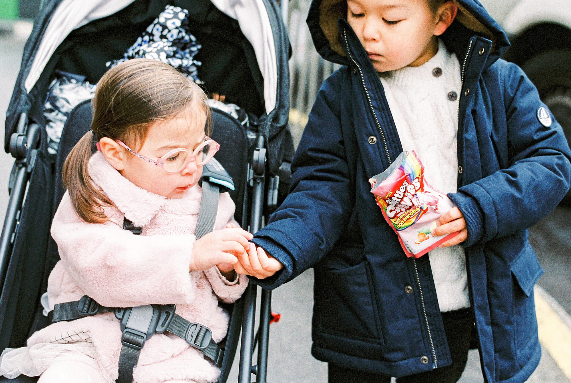Two young children bundled up sharing candy in Paris