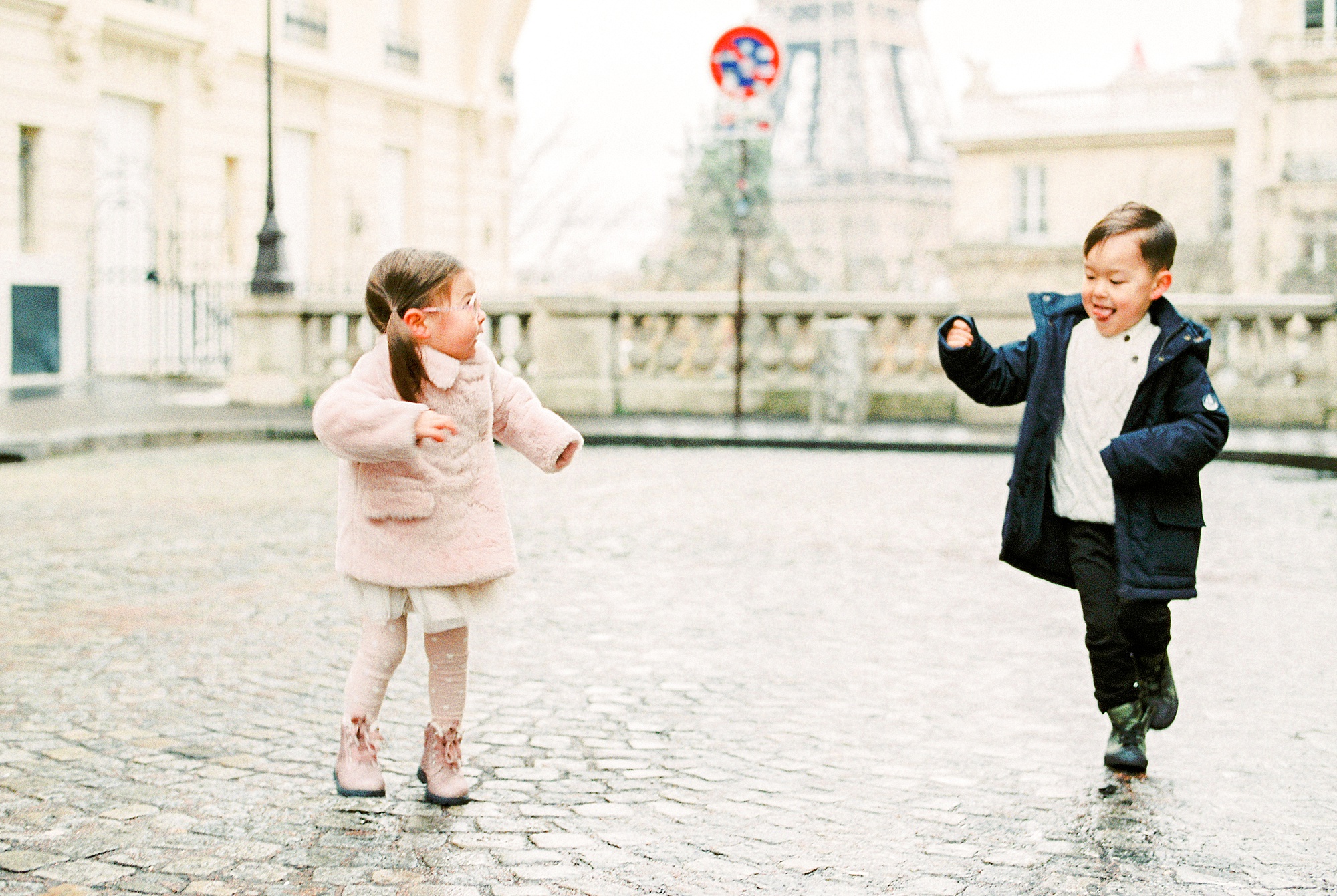 Two young children jumping at the Eiffel Tower
