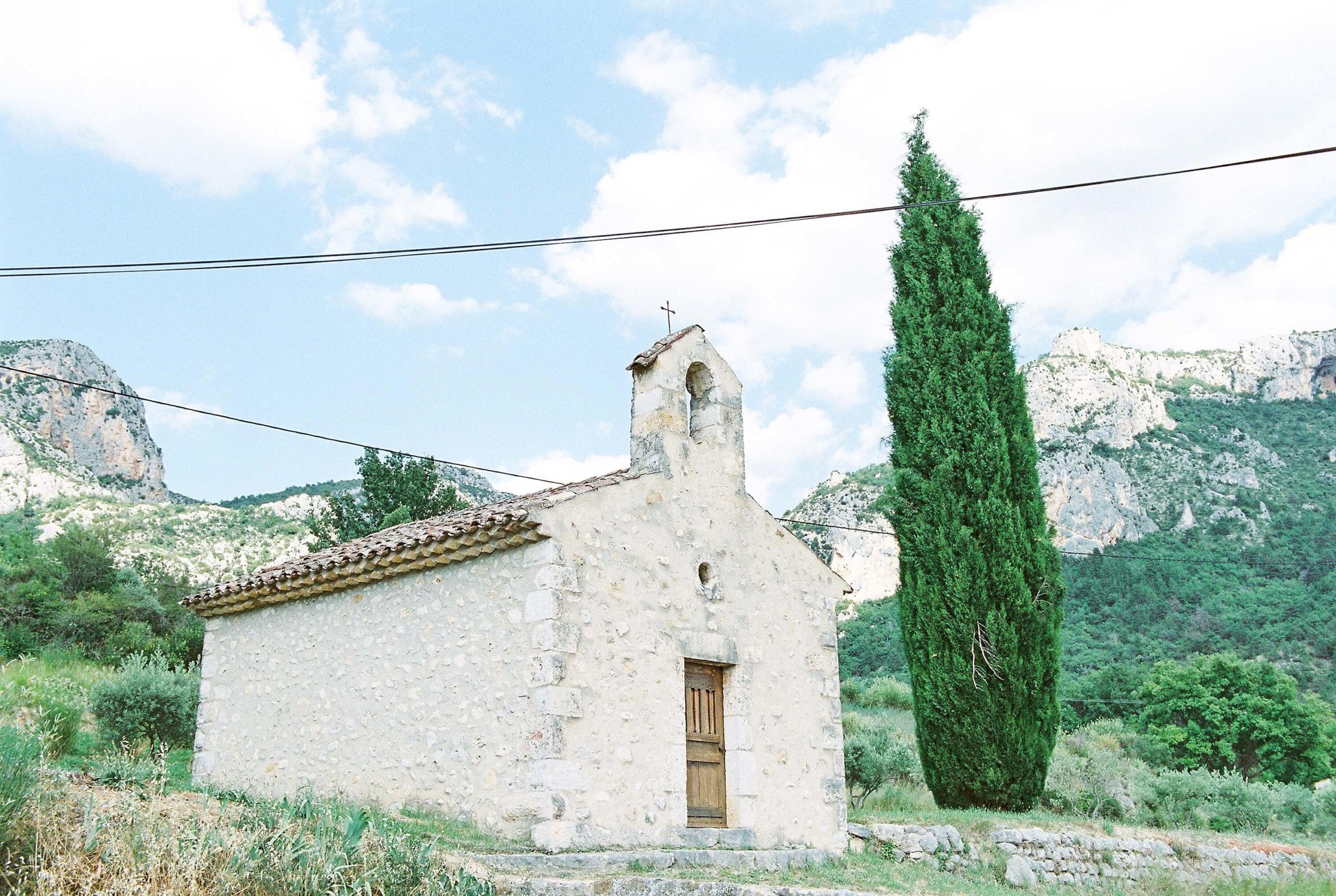 things to do in provence france: drive through the Verdon mountain range. image of a old, quaint stone church in the mountains.
