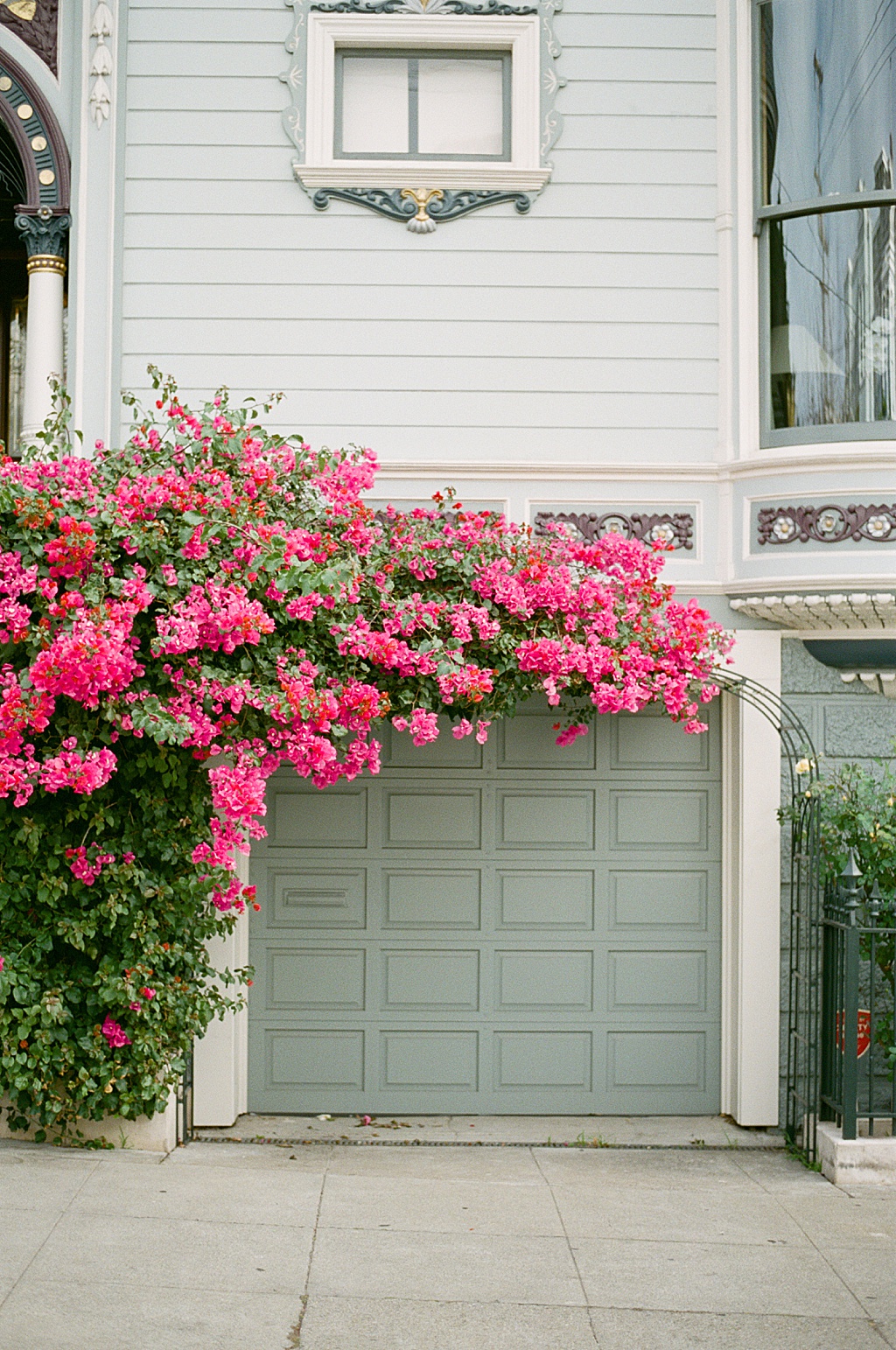 A cascade of magenta bougainvillea flowers over a powder sea green garage in San Francisco's Pacific Heights neighborhood on Divisadero Street.