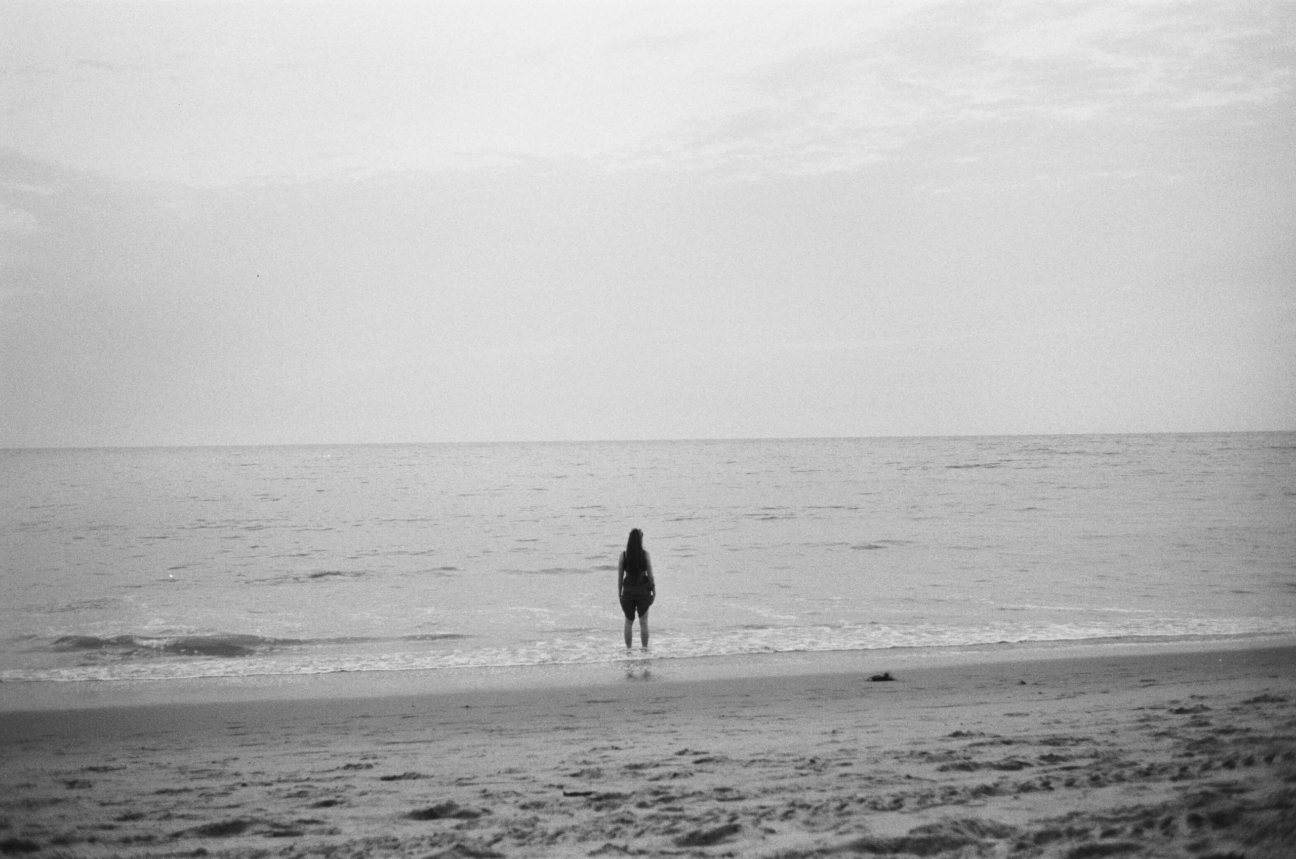 rollei 35 sample photo on Ilford HP5 black and white film. girl stands alone on a malibu beach at sunset.