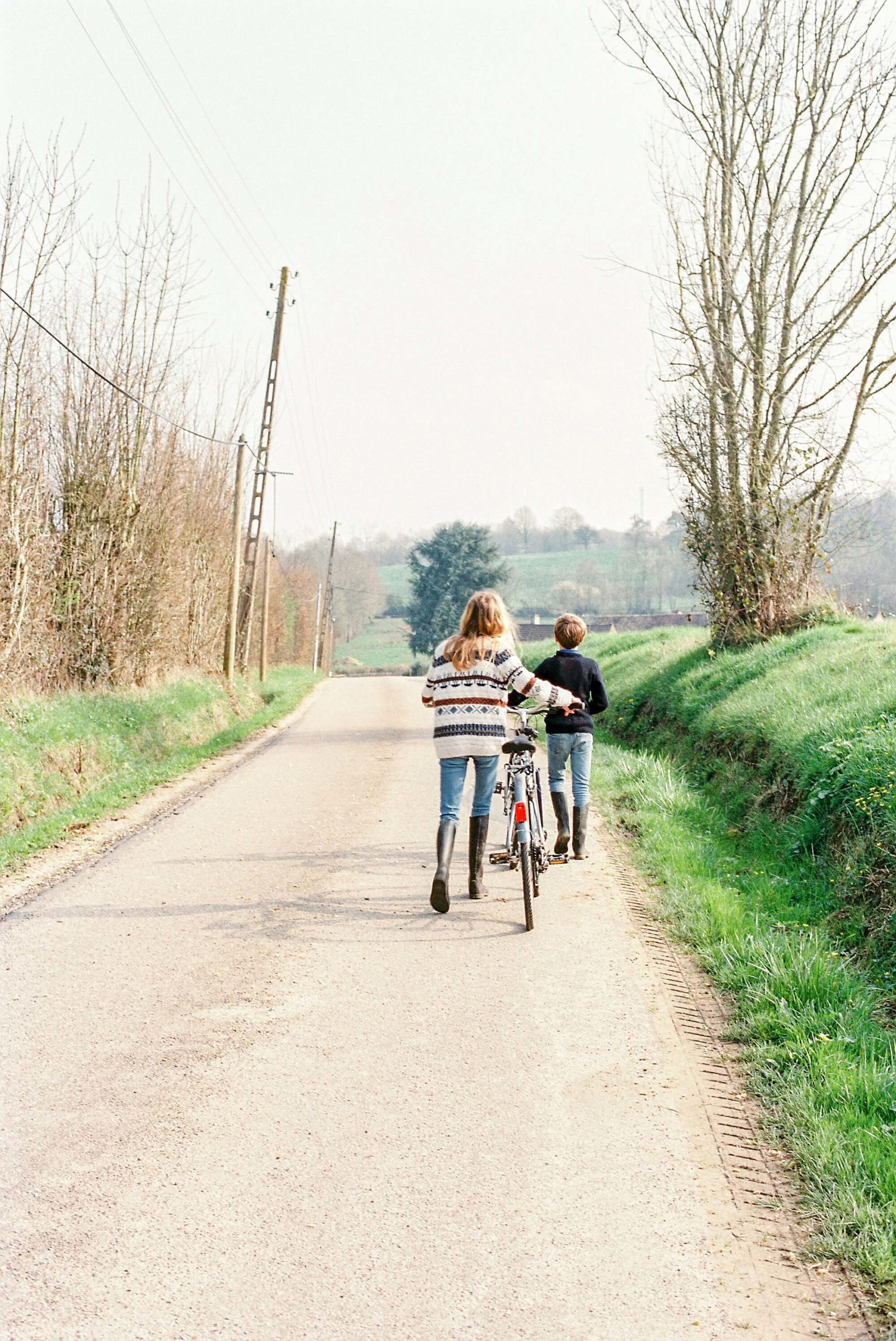 Two children push their bikes up a deserted country road in northern France.