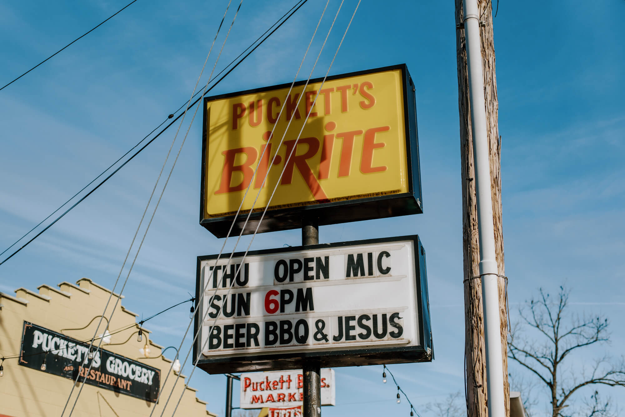 a sign in Leipers Fork, Tennessee reads "Puckett's Bi-Rite. Bear, BBQ, and Jesus."