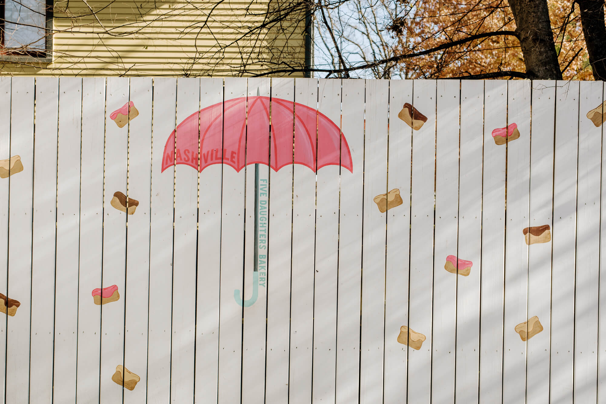 a mural at Five Daughters Bakery in 12 South Nashville. Doughnuts pelt a pink umbrella painted on a white fence.