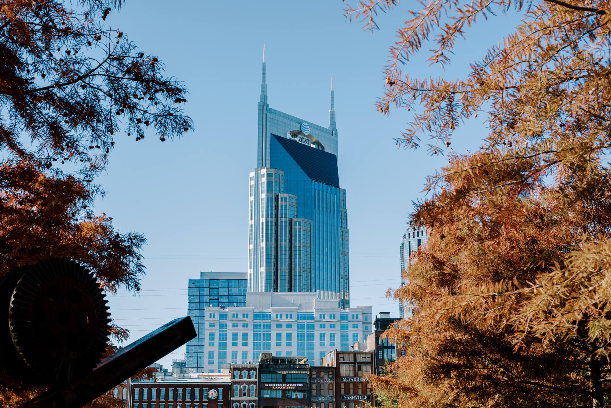 AT&T tower in Nashville framed between two trees in Cumberland Park on a sunny day