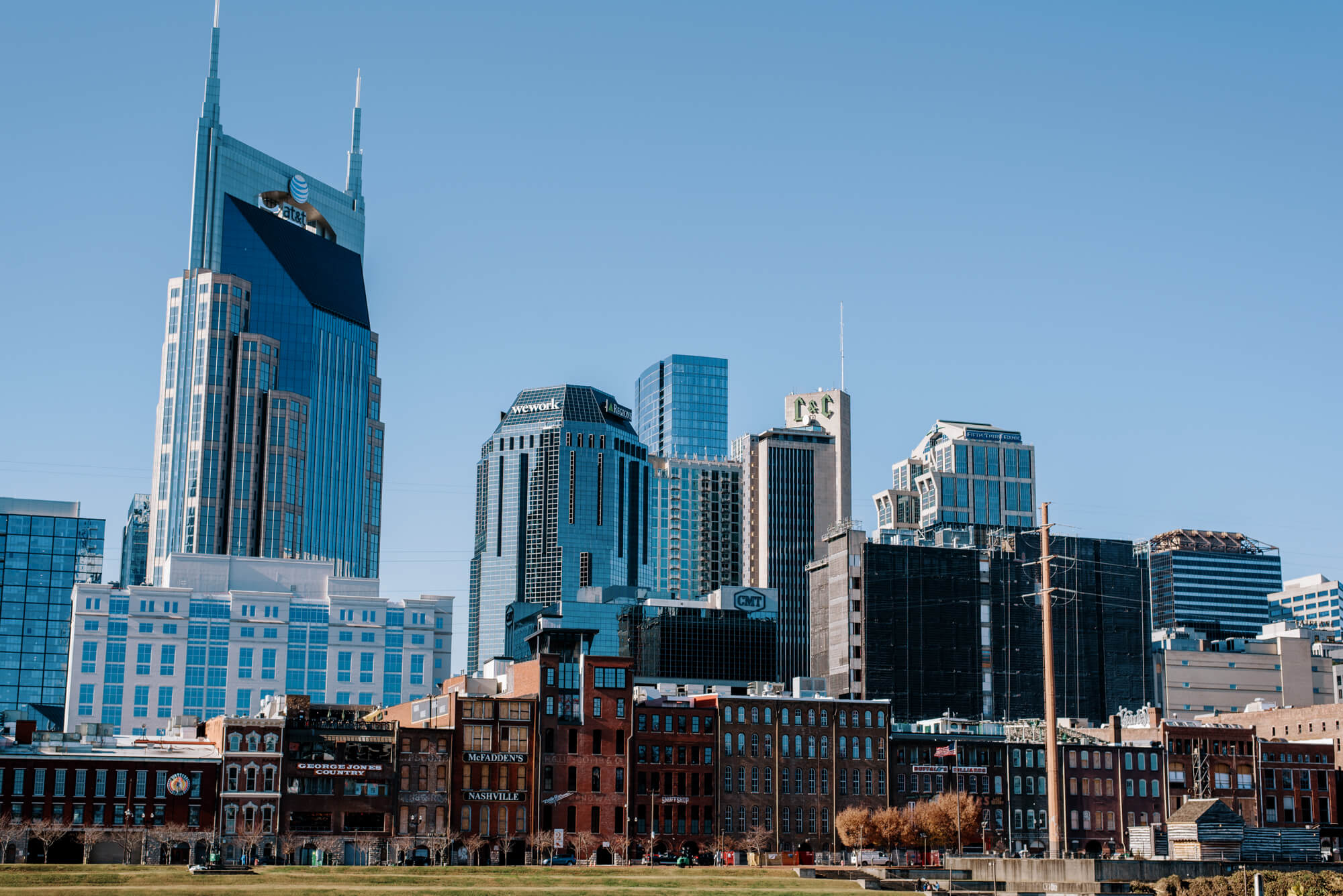 Nashville skyline from Cumberland Park featuring the AT&T tower rising above the rest on a sunny day.
